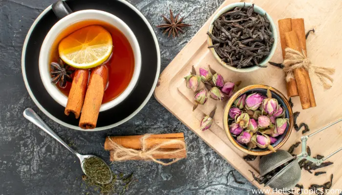 A top view of Asian herbal tea ingredients including lemon, cinnamon, tea leaves, and rose buds displayed to show how to brew Asian herbal tea