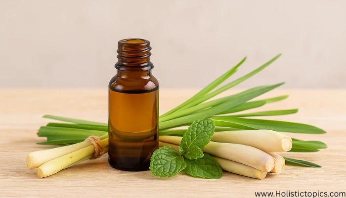 Amber bottle of lemongrass essential oil placed with fresh lemongrass stalks and mint leaves, supporting essential oils for energy cleansing routines